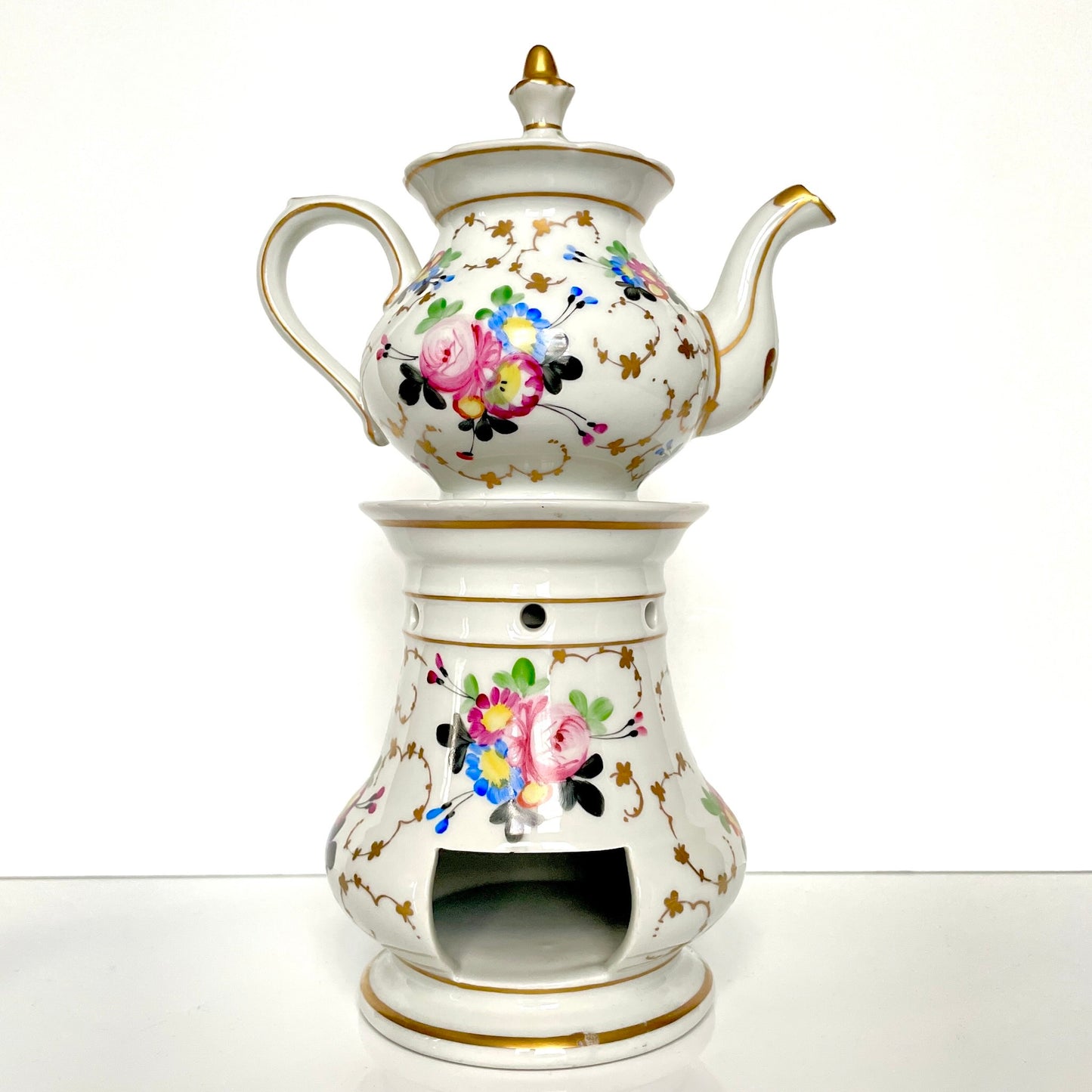 This is a Paris porcelain tisanière (herbal teapot with warmer) from the early 20th century. It features a hand-painted polychrome floral design with gilded accents.