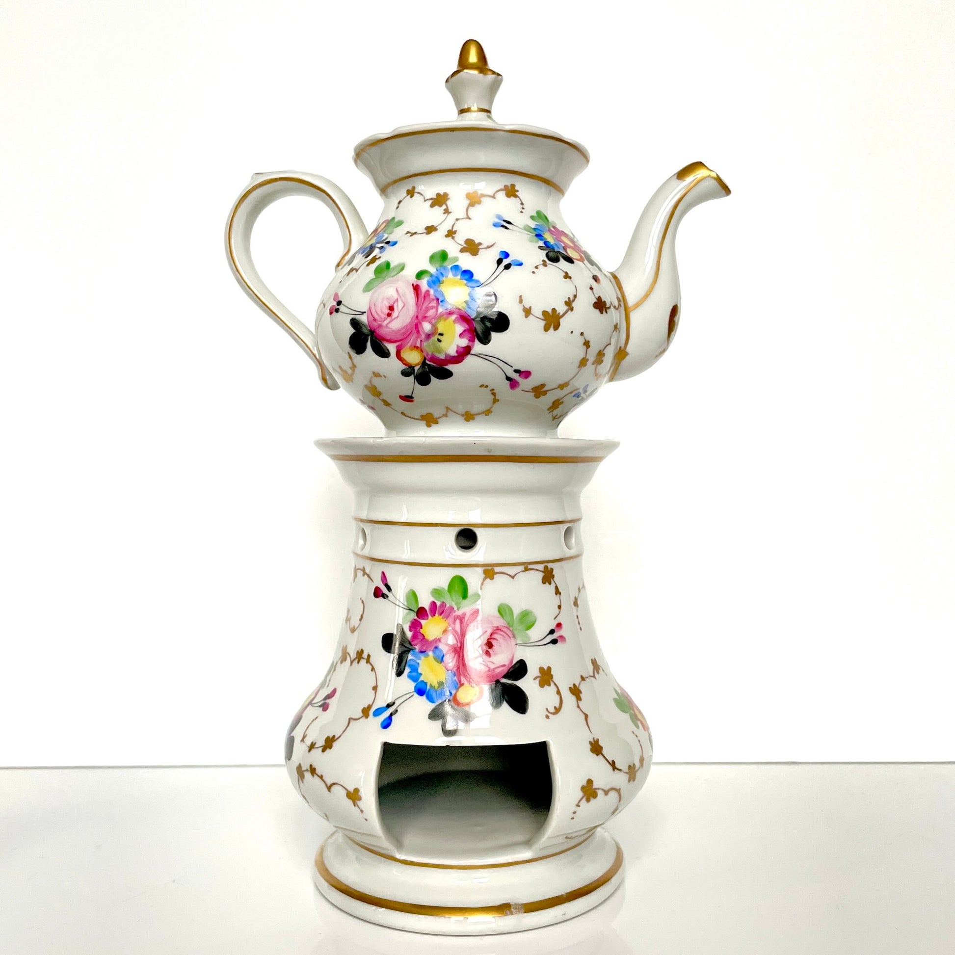 This is a Paris porcelain tisanière (herbal teapot with warmer) from the early 20th century. It features a hand-painted polychrome floral design with gilded accents.