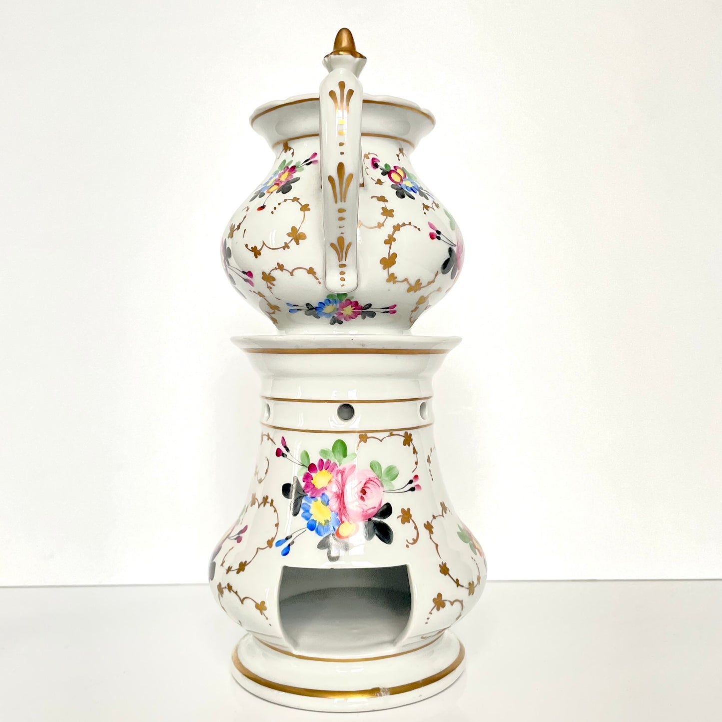 This is a Paris porcelain tisanière (herbal teapot with warmer) from the early 20th century. It features a hand-painted polychrome floral design with gilded accents.