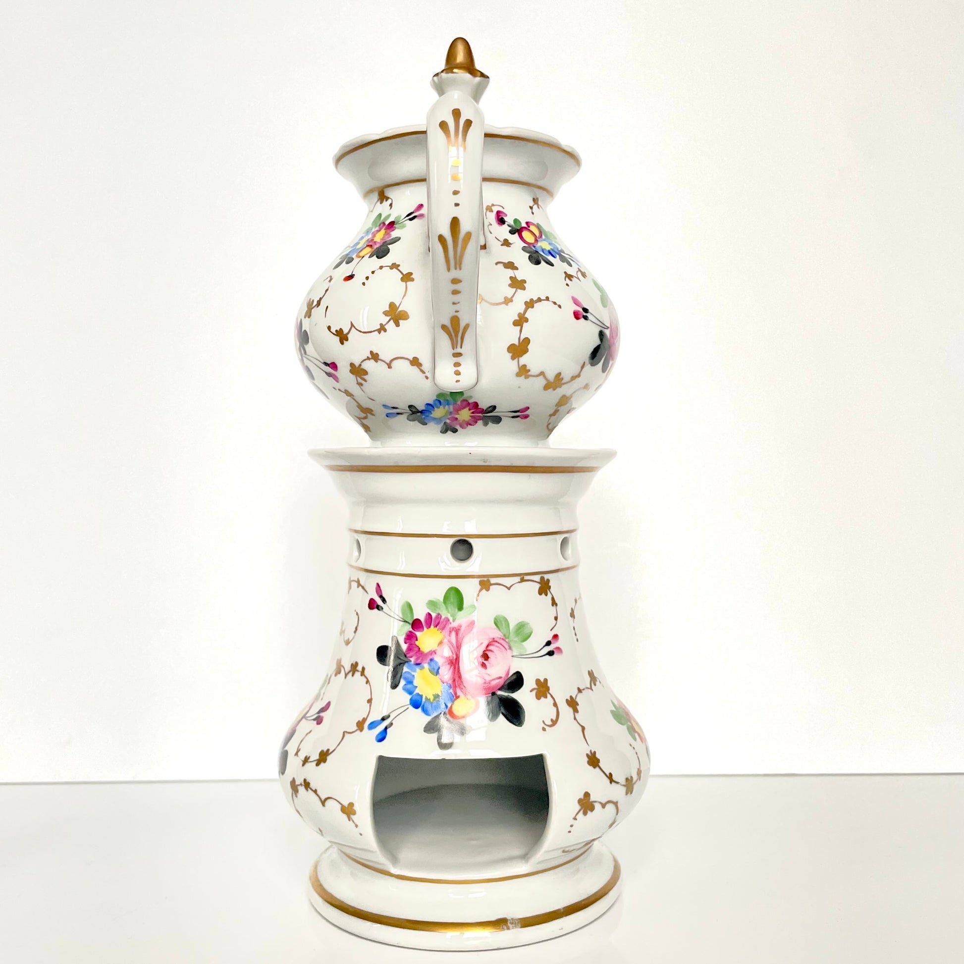 This is a Paris porcelain tisanière (herbal teapot with warmer) from the early 20th century. It features a hand-painted polychrome floral design with gilded accents.