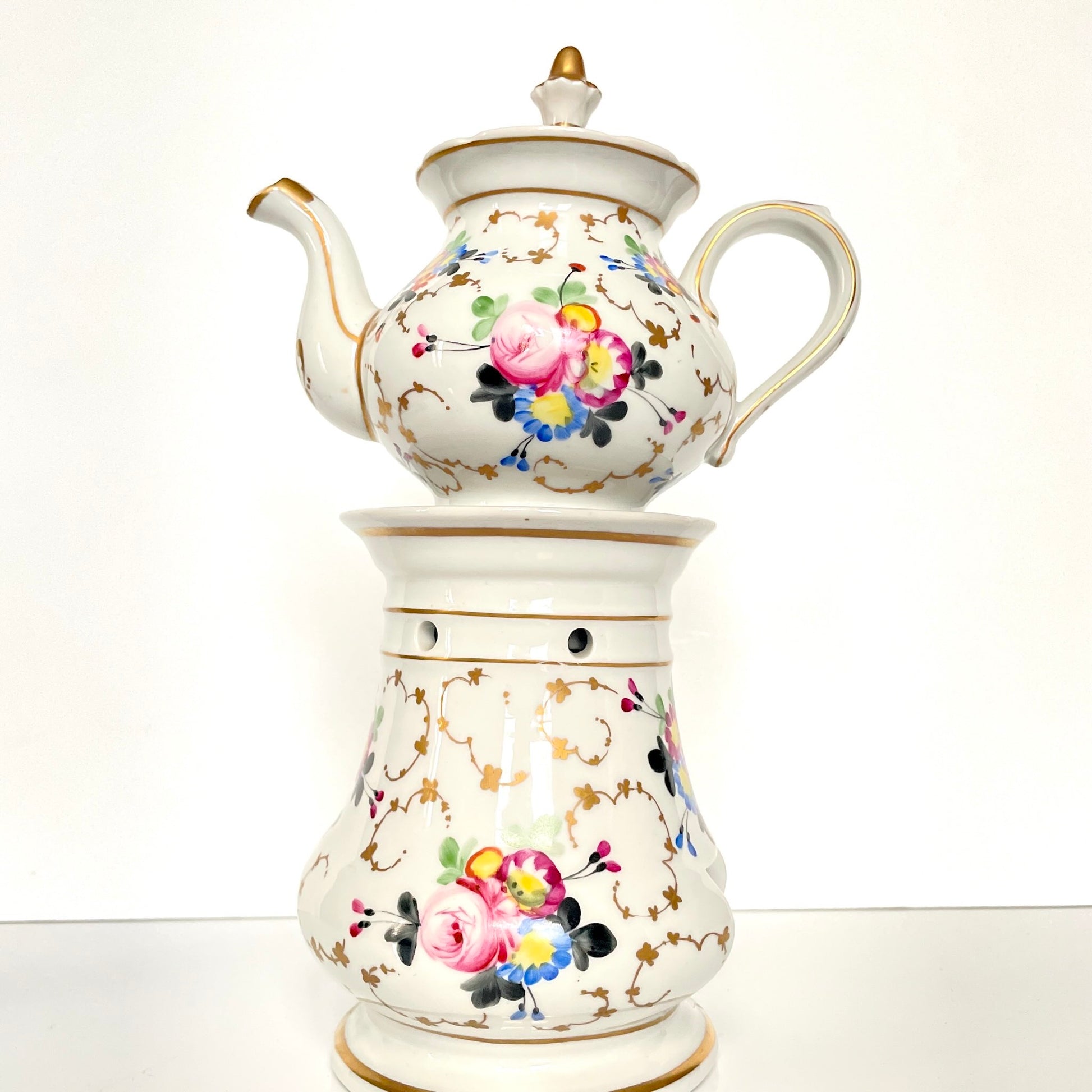 This is a Paris porcelain tisanière (herbal teapot with warmer) from the early 20th century. It features a hand-painted polychrome floral design with gilded accents.