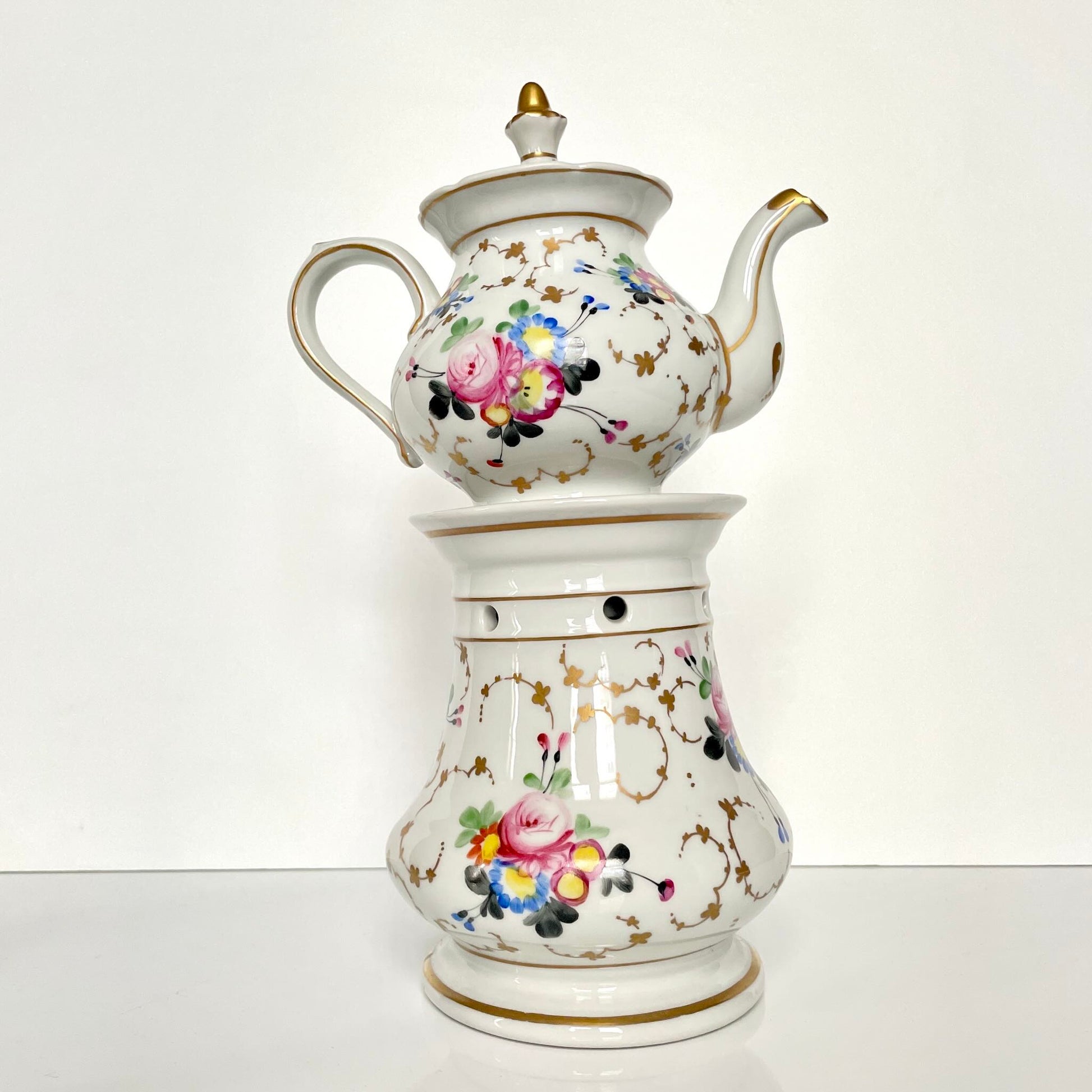 This is a Paris porcelain tisanière (herbal teapot with warmer) from the early 20th century. It features a hand-painted polychrome floral design with gilded accents.